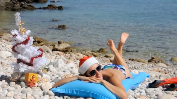 Young woman relaxing on the beach with christmas tree — Stock Video