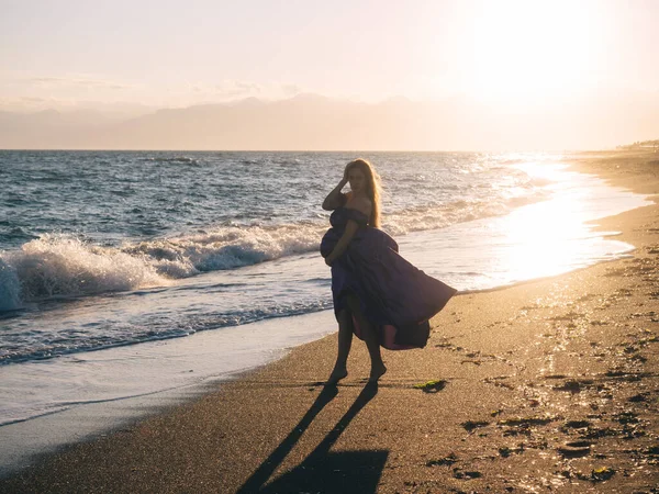 若いです女性でドレス単独で海によって歩く — ストック写真
