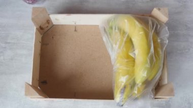 Kadın paketli meyve ve sebzeleri kutuya koydu.