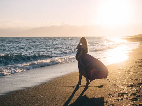 Jeune femme en robe marchant seule au bord de la mer — Photo