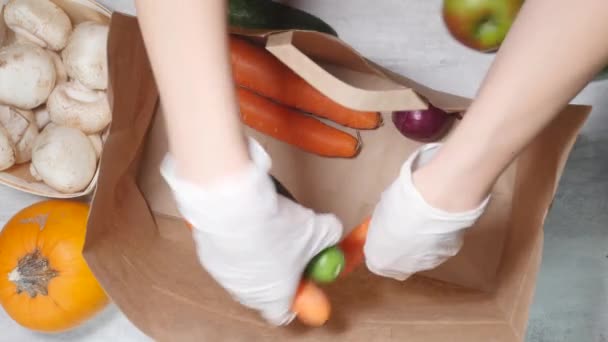 Kobieta wkłada owoce i warzywa do tekturowej torby. — Wideo stockowe