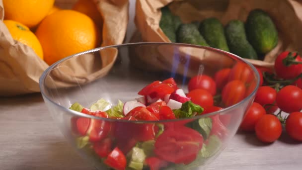 Toevoeging van zout aan groentesalade van tomaten, komkommers en sla — Stockvideo