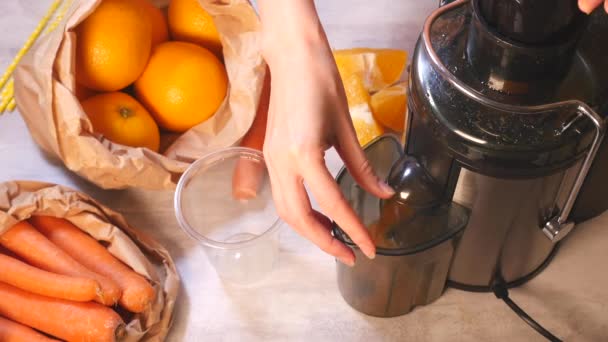Γυναικεία χέρια που ετοιμάζουν φρέσκο καρότο και χυμό πορτοκάλι — Αρχείο Βίντεο
