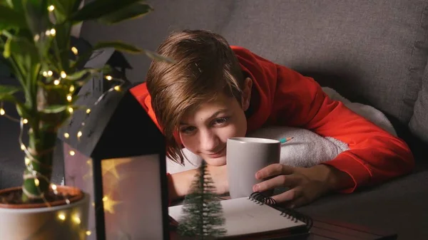 Leuke jongen met beker liggend op de bank — Stockfoto