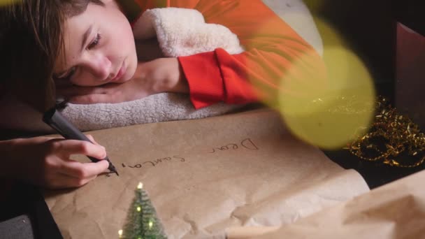 Мальчик-подросток пишет Санте длинное письмо — стоковое видео