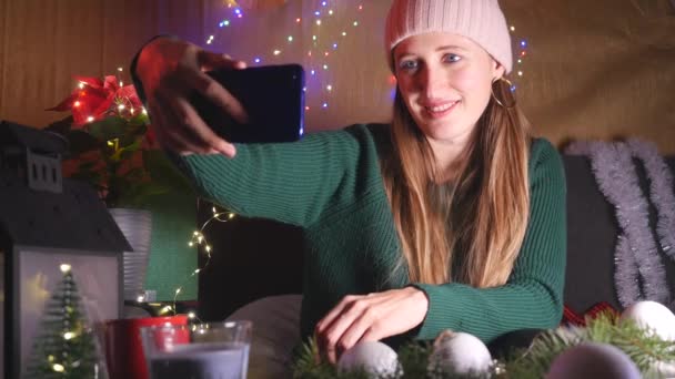 Giovane donna felice in cappello prendere un selfie su sfondo di Natale — Video Stock