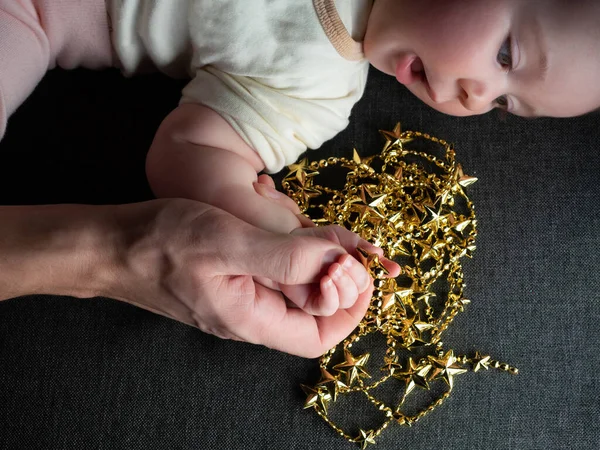 Primer plano del padre sosteniendo la mano del bebé en el sofá de fondo Navidad —  Fotos de Stock