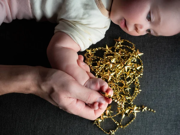 Primer plano del padre sosteniendo la mano del bebé en el sofá de fondo Navidad —  Fotos de Stock