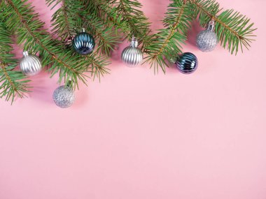 Pembe üzerinde noel topları olan fidan dalları 