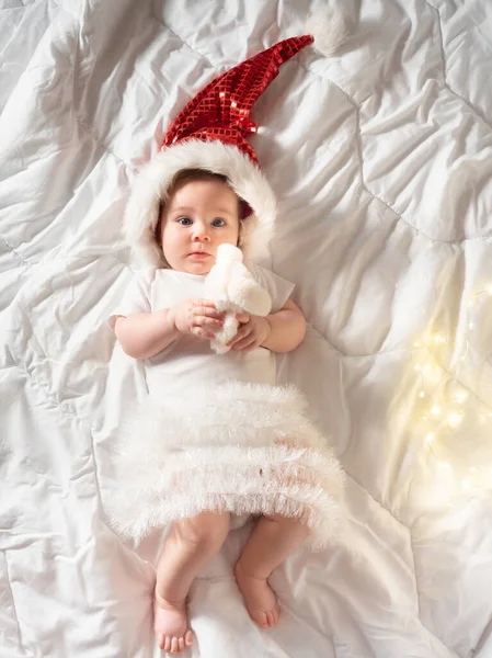 Engraçado bebê menina deitada na cama em roupas de Natal — Fotografia de Stock