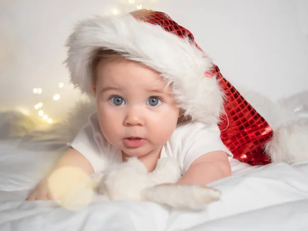 Adorable petite fille dans le chapeau de Père Noël couché sur le lit — Photo