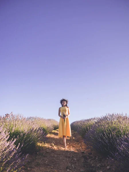 美しい女性で黄色のドレスで立って花束でラベンダー畑 — ストック写真