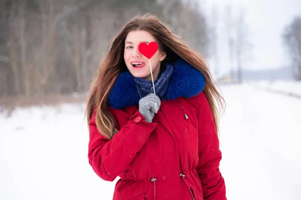 Young pretty woman in red holding heart on stick outdoors — Stock Photo, Image