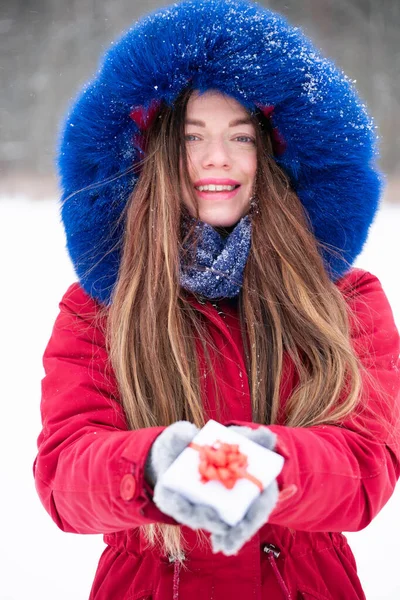 Young smiling woman in red hold gift box outdoors — Stock Photo, Image