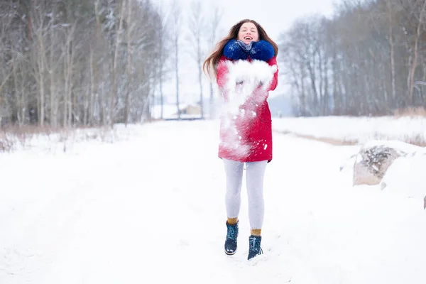 Jonge vrouw in rode jas genieten van besneeuwde winter — Stockfoto