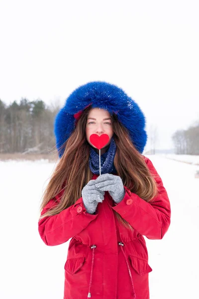 Young pretty woman in red holding heart on stick outdoors — Stock Photo, Image
