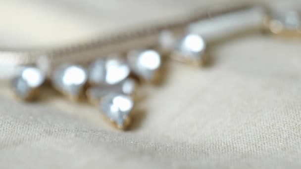 Закрыть вид на украшения из ожерелья, лежащие на платье — стоковое видео
