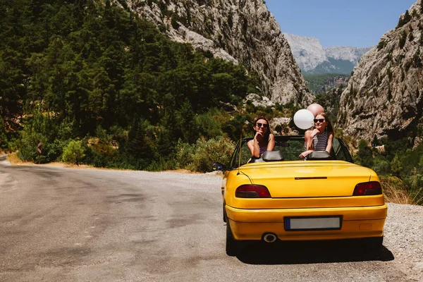 Deux jeunes femmes en voiture jaune profitant de vacances — Photo