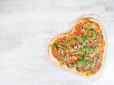Gri masada kalp şeklinde vejetaryen pizza.