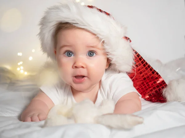 Adorable petite fille dans le chapeau de Père Noël couché sur le lit — Photo