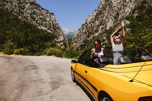 Two young woman in yellow car enjoying vacation — Stock Photo, Image