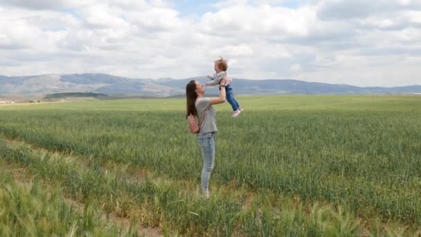 Счастливая молодая мама играет на открытом воздухе со своим маленьким ребенком — стоковое видео