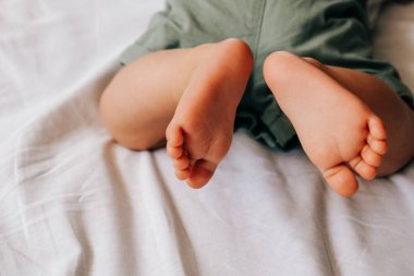 Beyaz çarşafta 8 aylık şirin bebek ayakları.