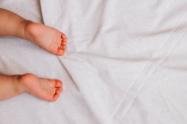 Beyaz çarşafta 6 aylık şirin bebek ayakları.