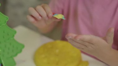  Kız, plastik bir Noel ağacı için renkli kilden Noel ağacı süslemeleri yapıyor.
