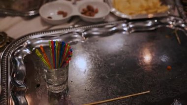 Boş tabaklarla dolu özenle hazırlanmış bir yemekten sonra bir dizi renkli şiş gümüş tepside duruyor..