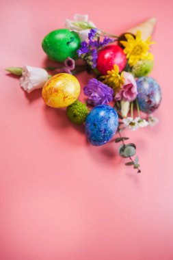 Güzel bir buket bahar çiçeği ve pembe arka planda dondurmalı paskalya yumurtası. Kopyalama alanı olan üst görünüm. Mutlu Paskalya tebrik kartları..