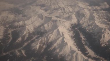 Kış günü gökyüzünde karla kaplı bir uçaktan alınan kuş bakışı dağlar..