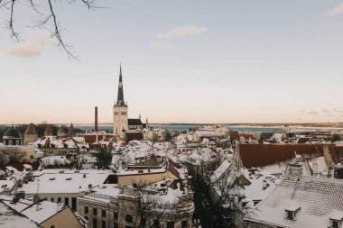 İnsanlar Tallinn sokaklarında yürür, kar ve temiz gökyüzünün altındaki tarihi mimarinin tadını çıkarırlar..