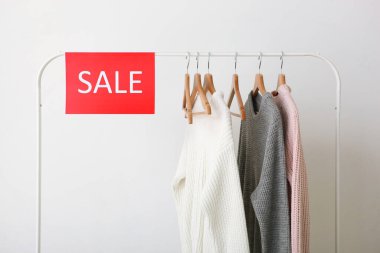 Tırabzanda giysiler ve satış tabelası. Son satış, indirimler.