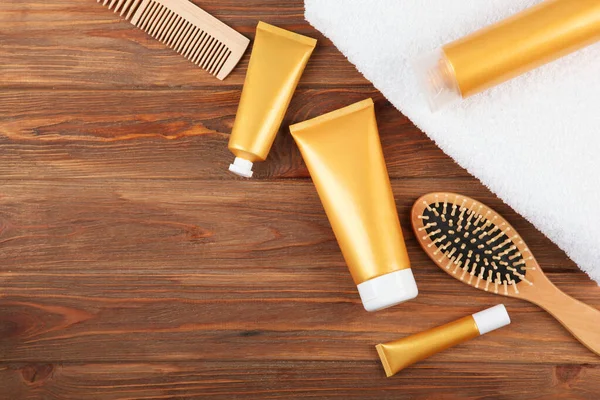 A lock of blonde hair, hair care products and a comb on a colored background top view. set of cosmetics for hair care