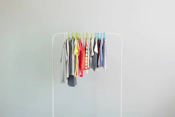 Ropa de los niños en una percha sobre un fondo de color. Ropa de niños, compras de niños. — Foto de Stock