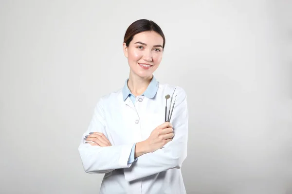Jonge vrouw tandarts op lichte achtergrond met plaats om tekst in te voegen — Stockfoto
