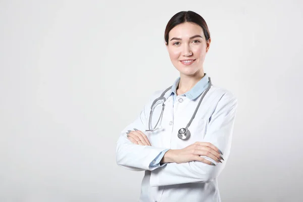 Jonge vrouw arts op lichte achtergrond met plaats om tekst te plaatsen — Stockfoto