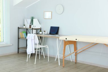 Kanepesi ve çalışma masası olan bir doktor ofisi. Doktorların işyeri 