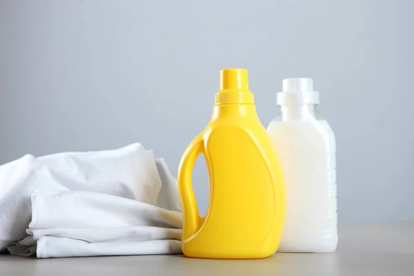 Lavanderia detergente garrafas e roupas na mesa. Produtos químicos para uso doméstico — Fotografia de Stock