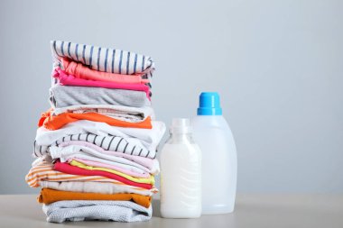 Çamaşır deterjanı şişeleri ve giysiler masanın üzerinde. Ev kimyasalları.
