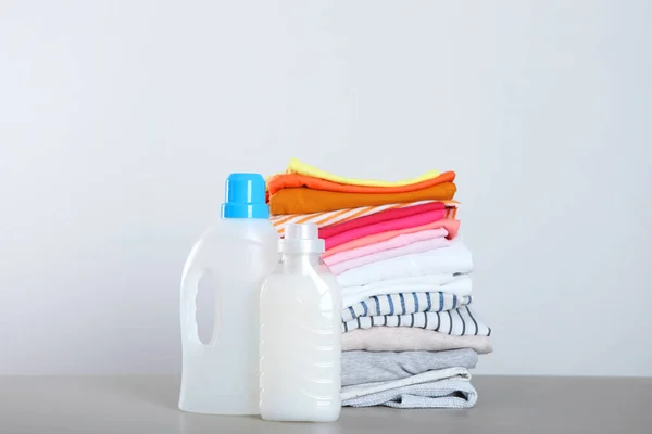 Butelki po detergentach i ubrania na stole. Chemikalia dla gospodarstw domowych — Zdjęcie stockowe