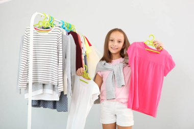 Küçük tatlı kız soyunma odasında kıyafet seçiyor.