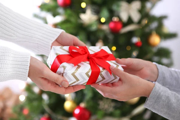 Cadeau de Noël ou du Nouvel An dans les mains sur le fond d'un intérieur décoré. Offrez des cadeaux de Noël — Photo