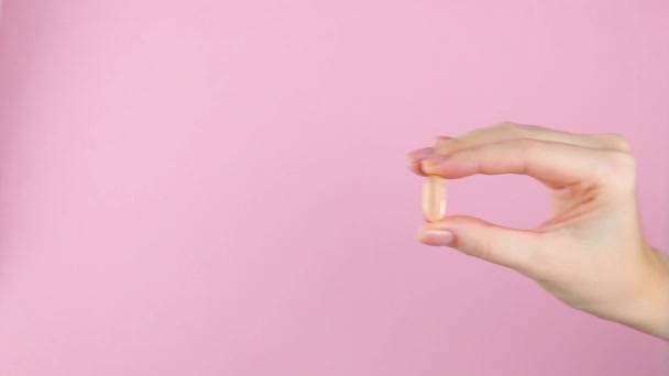 Omega 3 kapsułka w kobiecej dłoni na jasnym kolorowym tle zbliżenie. — Wideo stockowe