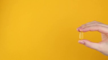 Omega 3 kapsülü, parlak renkli arka planda bir kadının elinde.. 