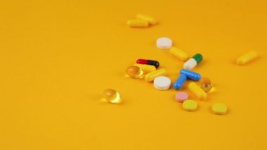 Turuncu arka planda farklı renk ve boyutlarda haplar..