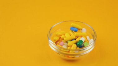 Turuncu arka planda farklı renk ve boyutlarda haplar..