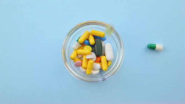 Pills of different colors and sizes on an orange background. — Stock Video