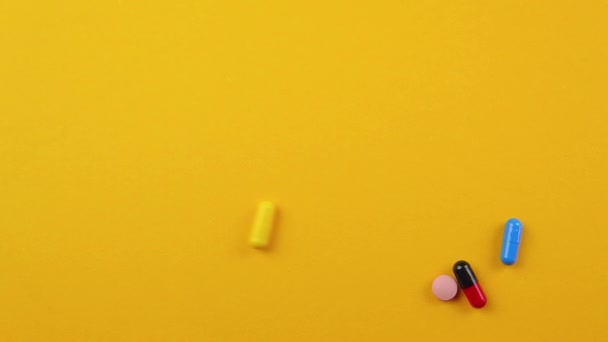 Pills of different colors and sizes on an orange background. — Stock Video